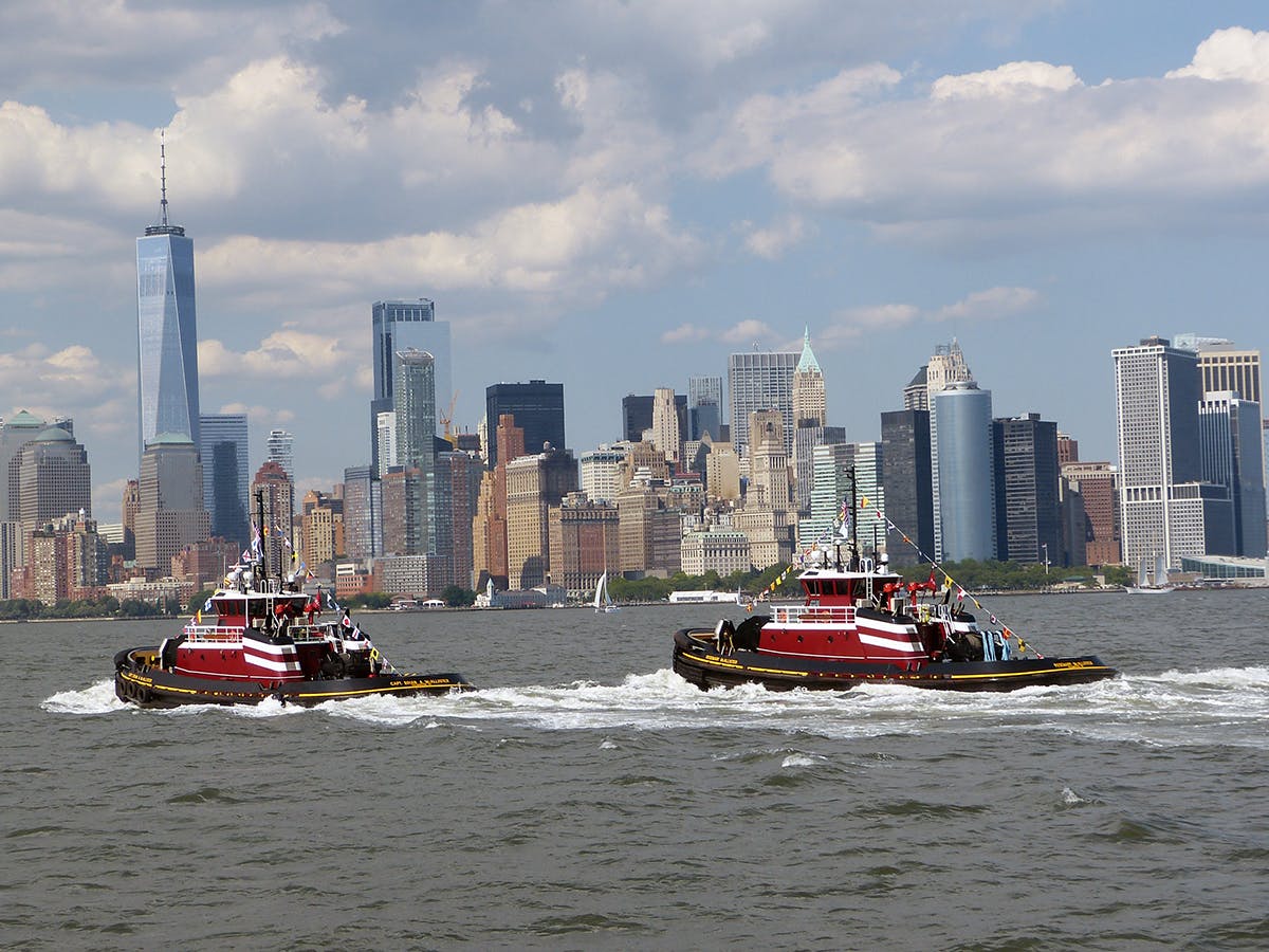 The tugs Capt. Brian A. McAllister and Rosemary McAllister in New York harbor with the Freedom Tower and downtown NYC in the background.