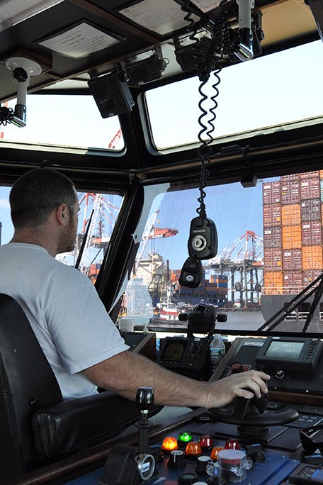 A captain at the controls in the wheelhouse of a McAllister tractor tug.