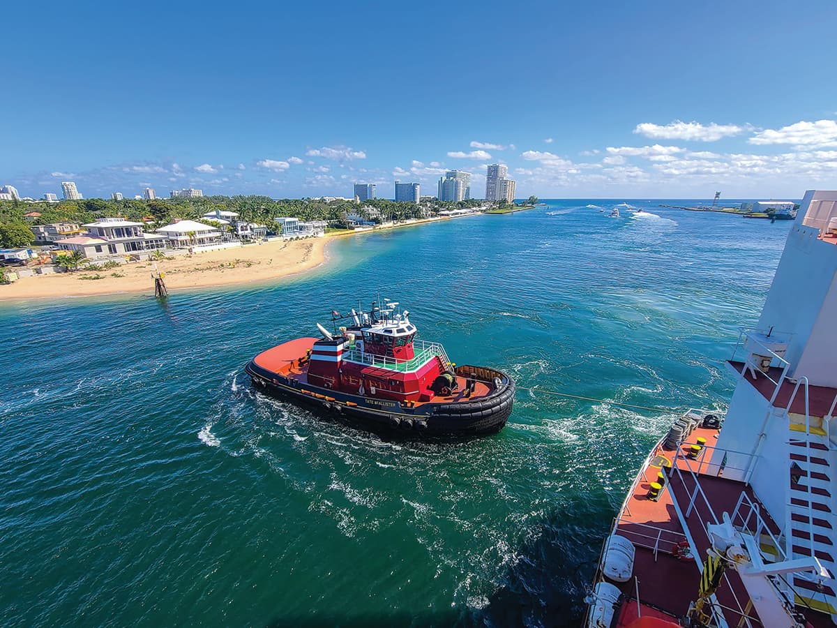 The Tate McAllister, with a line up to the stern, guides a ship into Port Everglades, Florida.